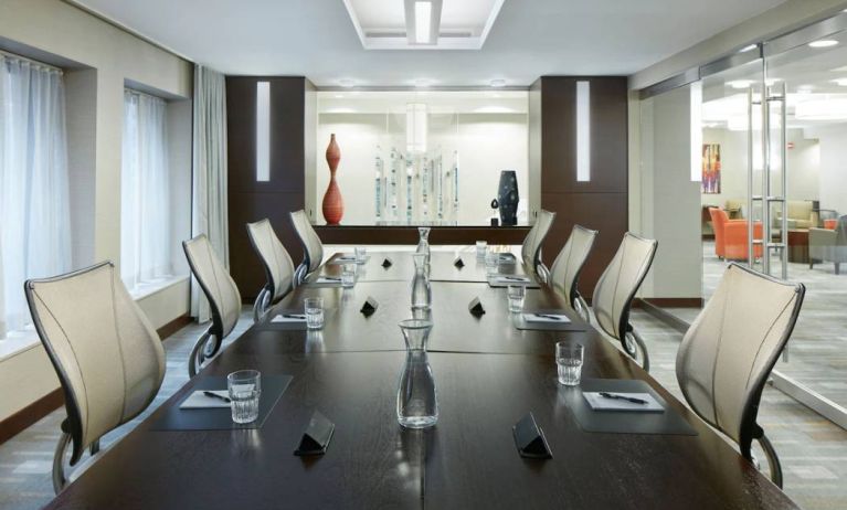 Meeting room in the Club Quarters Hotel Wacker At Michigan, with long table, surrounding chairs, and nearby windows.