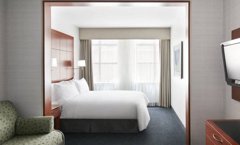 One of the Club Quarters Hotel Central Loop’s guest rooms, featuring bed, chair, and window.