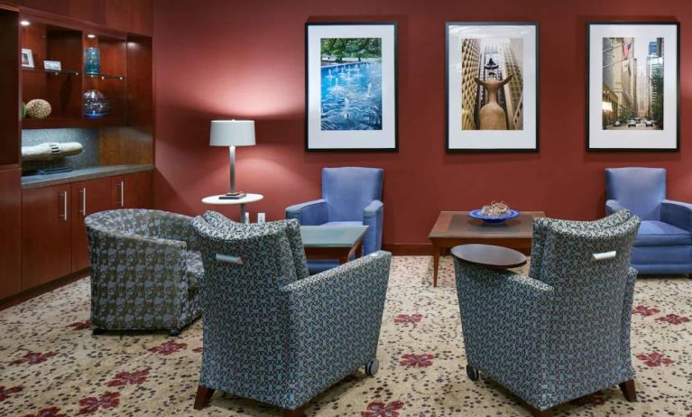 Hotel lounge, with armchairs and coffee tables, plus art on the wall.