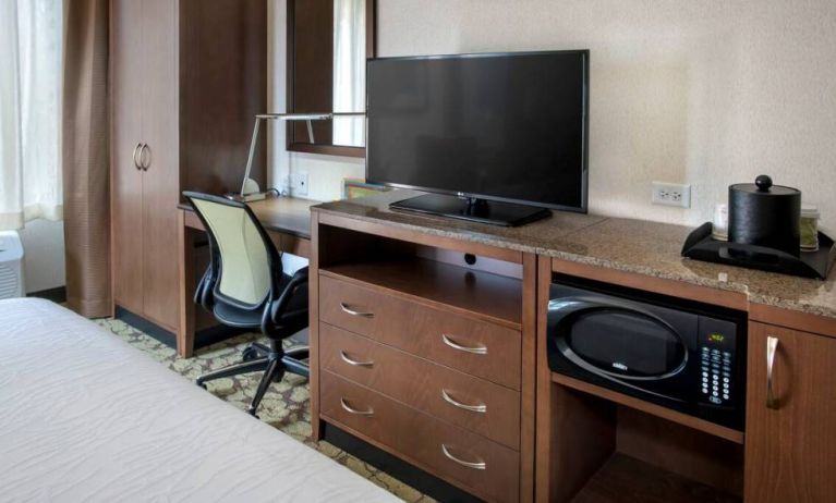 Closer view of an in-room workspace, with chair and desk for business, and both a lamp and window nearby.