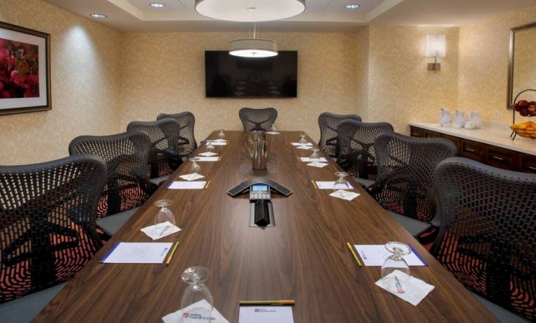 Meeting room in the Hilton Garden Inn Chicago Downtown Riverwalk, with long table, surrounding chairs and large TV.