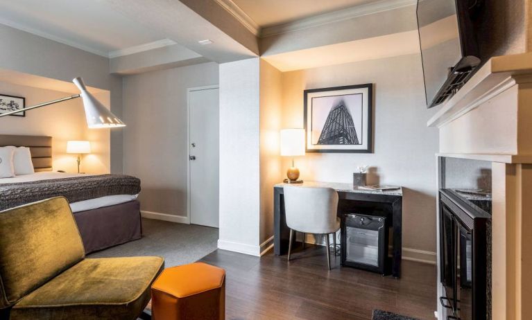 Guest room in Claridge House, featuring large bed, TV, and workspace desk and chair.