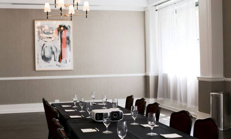 One of the hotel’s meeting room facilities, with long table, surrounding chairs, art on the wall, and large window.