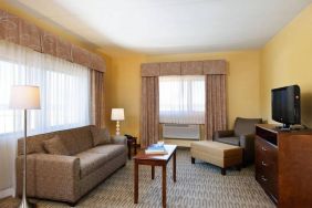 Guest room lounge in Holiday Inn Express Philadelphia Airport, with sofa, chair, TV, and foot stool.