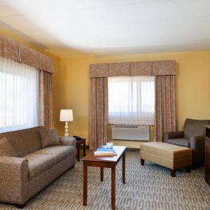 Guest room lounge in Holiday Inn Express Philadelphia Airport, with sofa, chair, TV, and foot stool.