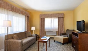 Guest room lounge in Holiday Inn Express Philadelphia Airport, with sofa, chair, TV, and foot stool.