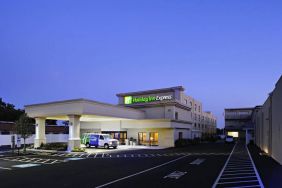 The exterior of the hotel, which provides shade/cover from the rain for the entranceway, and space for parking.