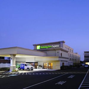 The exterior of the hotel, which provides shade/cover from the rain for the entranceway, and space for parking.