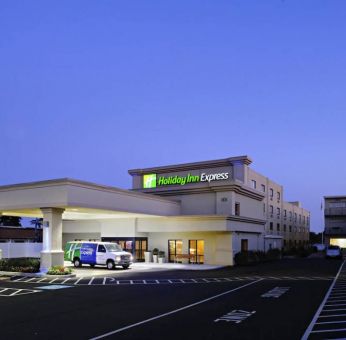 The exterior of the hotel, which provides shade/cover from the rain for the entranceway, and space for parking.