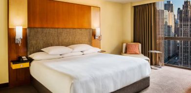 Double bed guest room in Hyatt Regency Chicago, with large window offering views of the urban vista.