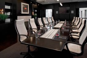 Stylishly dark meeting room, with long black table and white chairs around it.