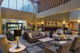 Lounge in the Sheraton Houston Brookhollow Hotel lobby, with array of comfy chairs and sofas, plus small tables.