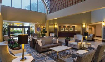 Lounge in the Sheraton Houston Brookhollow Hotel lobby, with array of comfy chairs and sofas, plus small tables.