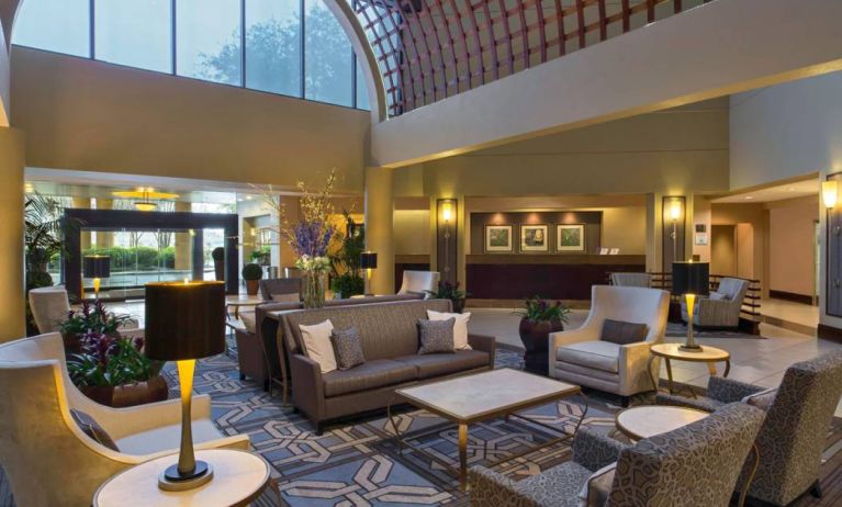 Lounge in the Sheraton Houston Brookhollow Hotel lobby, with array of comfy chairs and sofas, plus small tables.