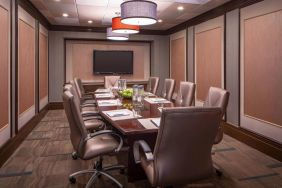 Hotel meeting room, featuring long wooden table and surrounding leather chairs.