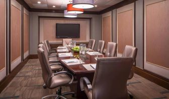 Hotel meeting room, featuring long wooden table and surrounding leather chairs.