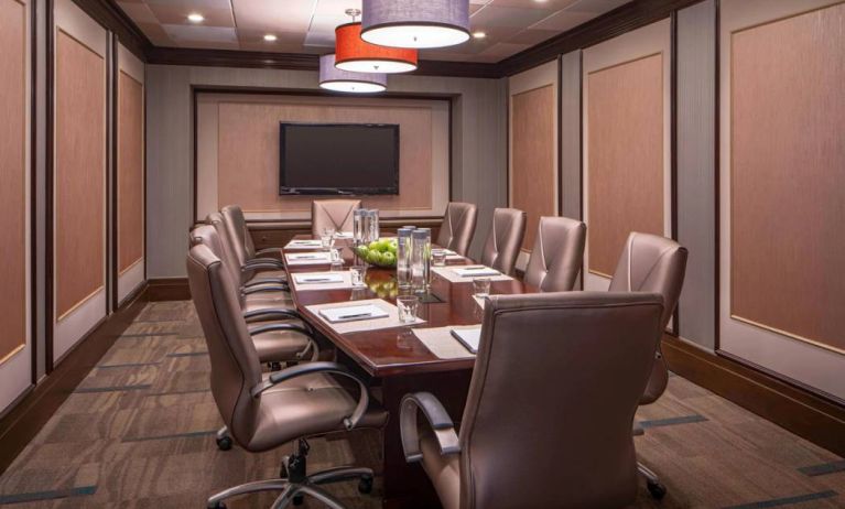 Hotel meeting room, featuring long wooden table and surrounding leather chairs.