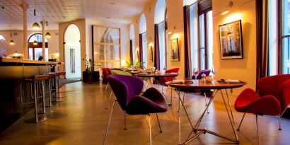 The hotel restaurant has a bar and small tables for diners to enjoy a refined breakfast experience.