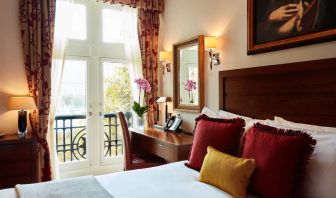 Double door view of outside with wooden desk workspace alongside guest queen bed.