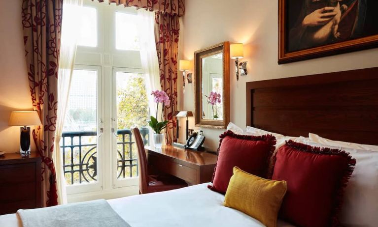 Double door view of outside with wooden desk workspace alongside guest queen bed.