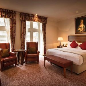 Deluxe king room at The Royal Horseguards Hotel, featuring numerous leather chairs, large windows, and a desk.