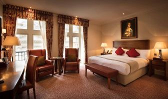 Deluxe king room at The Royal Horseguards Hotel, featuring numerous leather chairs, large windows, and a desk.