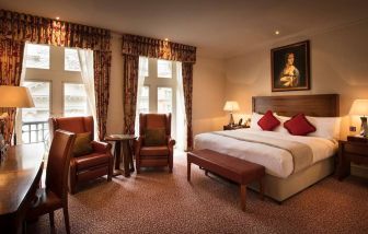 Deluxe king room at The Royal Horseguards Hotel, featuring numerous leather chairs, large windows, and a desk.