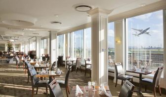 Sunlight room with floor to ceiling windows spanning the entire length of the wall to see planes takeoff and land at London Heathrow Airport.