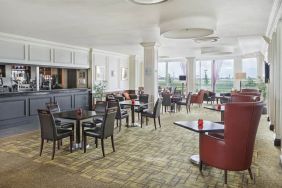 Bar with table and booth seating and floor to ceiling wall length windows showing Terminal 5 of London Heathrow.