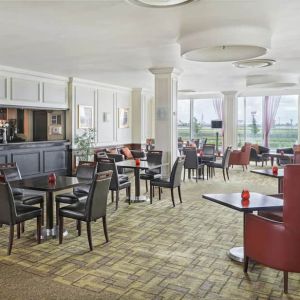 Bar with table and booth seating and floor to ceiling wall length windows showing Terminal 5 of London Heathrow.