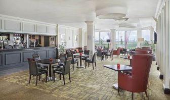 Bar with table and booth seating and floor to ceiling wall length windows showing Terminal 5 of London Heathrow.