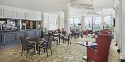 Bar with table and booth seating and floor to ceiling wall length windows showing Terminal 5 of London Heathrow.