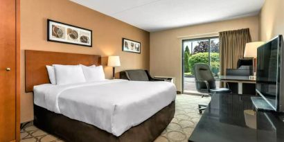 A double bed guest room within Comfort Inn Regina, containing a workspace desk and chair, plus large window.