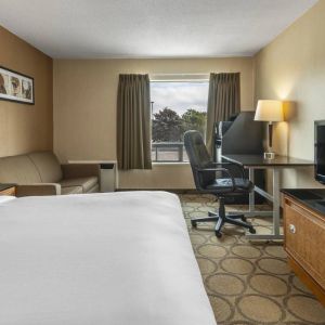 A guest room in the Comfort Inn Regina, with double bed, sofa, and widescreen television.