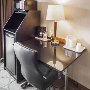 Closer shot of an in-room workspace, including chair, desk, lamp, and nearby window.