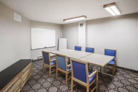 Hotel meeting room with space for half a dozen attendees around a table, and a whiteboard nearby.