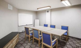 Hotel meeting room with space for half a dozen attendees around a table, and a whiteboard nearby.