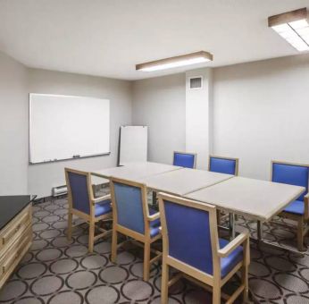 Hotel meeting room with space for half a dozen attendees around a table, and a whiteboard nearby.