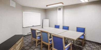 Hotel meeting room with space for half a dozen attendees around a table, and a whiteboard nearby.