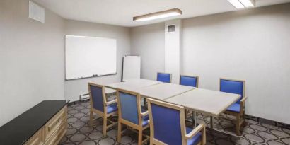 Hotel meeting room with space for half a dozen attendees around a table, and a whiteboard nearby.