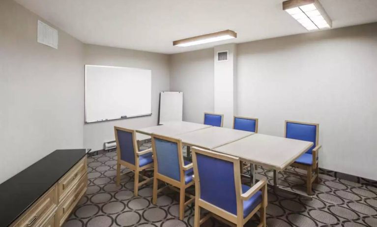 Hotel meeting room with space for half a dozen attendees around a table, and a whiteboard nearby.