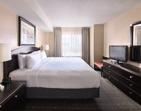 Double bed guest room in Les Suites Hotel Ottawa, with large window and TV.