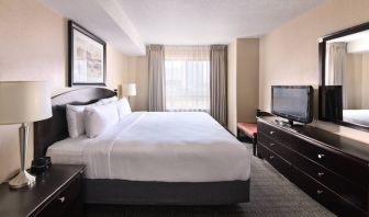 Double bed guest room in Les Suites Hotel Ottawa, with large window and TV.