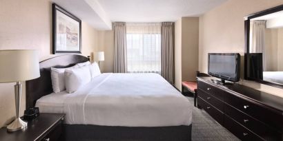 Double bed guest room in Les Suites Hotel Ottawa, with large window and TV.