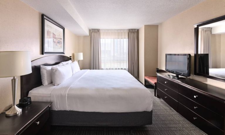 Double bed guest room in Les Suites Hotel Ottawa, with large window and TV.