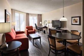 Guest room lounge in Les Suites Hotel Ottawa, with workspace desk and chair, plus sofa, chairs, and tables.