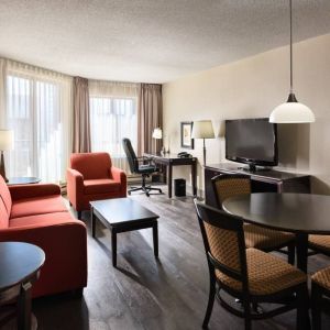 Guest room lounge in Les Suites Hotel Ottawa, with workspace desk and chair, plus sofa, chairs, and tables.