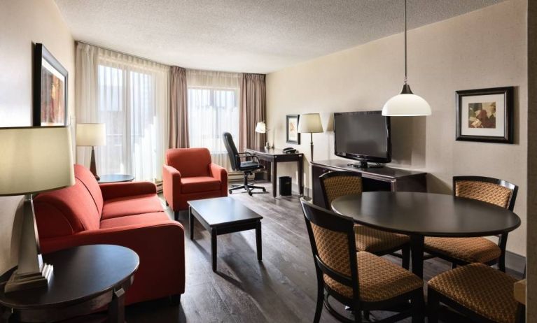 Guest room lounge in Les Suites Hotel Ottawa, with workspace desk and chair, plus sofa, chairs, and tables.