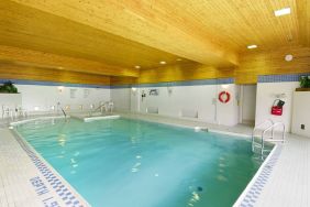 The hotel’s indoor pool is brightly lit and has chairs by the side.