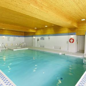 The hotel’s indoor pool is brightly lit and has chairs by the side.